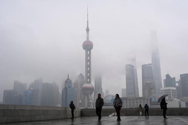 People walk on the Bund promenade along the Huangpu River in Shanghai on March 5, 2026. (Photo by Jade GAO / AFP)