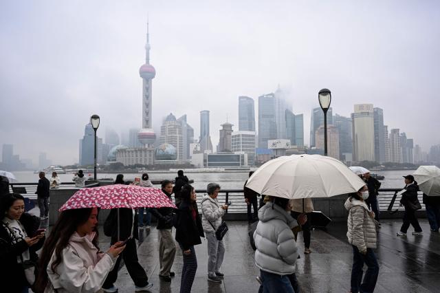 People walk on the Bund promenade along the Huangpu River in Shanghai on March 5, 2026. (Photo by Jade GAO / AFP)
