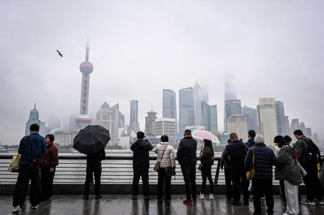 People visit the Bund promenade along the Huangpu River in Shanghai on March 5, 2026. (Photo by Jade GAO / AFP)