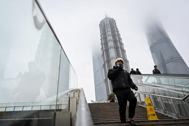 A man speaking on his phone walks down the steps at the financial district of Lujiazui in Shanghai on March 5, 2026. (Photo by Jade GAO / AFP)