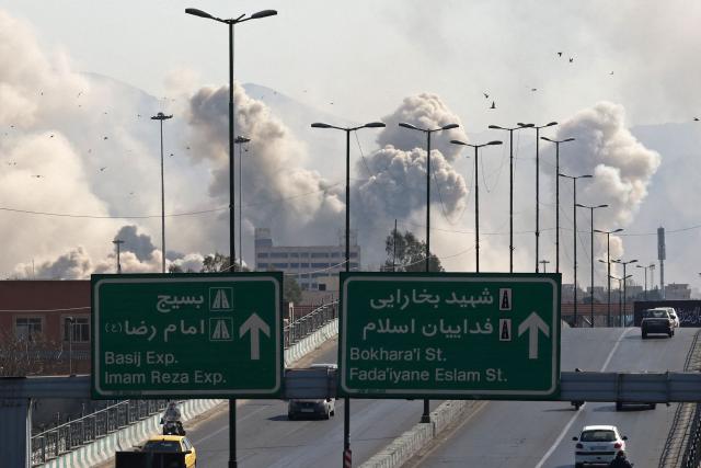 Vehicles drive along an expressway against the backdrop of smoke rising after a strike on the Iranian capital of Tehran on March 5, 2026. Israel pounded Tehran with fresh strikes and Iran targeted Kurdish guerilla groups in Iraq on March 5 as a spiralling war in the Middle East engulfed the entire region. (Photo by ATTA KENARE / AFP)