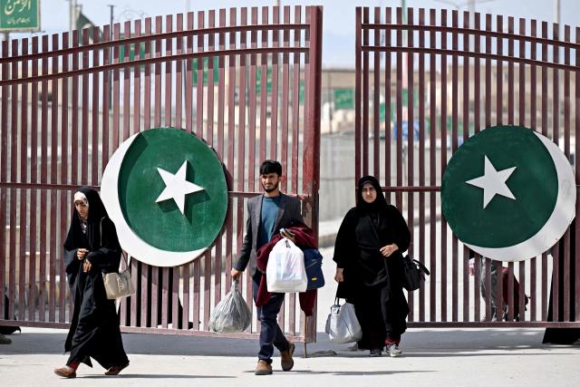 Pakistani nationals with their belongings walk across the Pakistan-Iran border at Taftan in Balochistan province on March 5, 2026, upon their arrival from Iran amid the Middle East war. Around 2,000 kilometres away (1,250 miles) in the far east of Iran, Pakistanis are flooding back to their country through the Taftan border crossing, sharing stories about a war none of them expected to be caught up in. (Photo by Banaras KHAN / AFP)