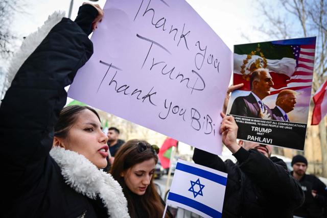 A member of the Iranian community to Romania holds a sign reading "Thank you Trump, thank you Bibi" during a protest in front of the Iranian Embassy in Bucharest on March 5, 2026. Around one hundred participants held placards and chanted slogans in support of Israeli-US strikes on Iran and for the son of the last Shah of Iran, Reza Pahlavi, the most prominent figure in the Iranian opposition in exile. (Photo by Daniel MIHAILESCU / AFP)