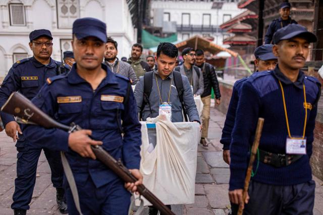 Security personnel escort as electoral officials carry ballot boxes to the counting centre after voting ends at a polling station during Nepal's general election in Kathmandu on March 5, 2026. Nepal voted on March 5 for a new parliament in a high-stakes showdown between an entrenched old guard and a powerful youth movement, six months after deadly anti-corruption protests toppled the government. (Photo by Prabin RANABHAT / AFP)