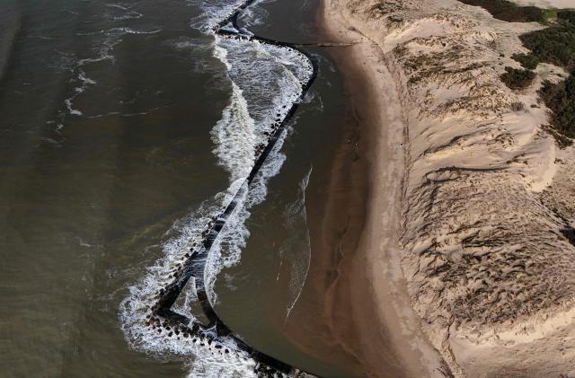 This aerial photograph shows waves breaking on wave-breakers dating back from the 19th century and also offering bathing pools at the summer, along the Atlantic Ocean in Soulac-sur-Mer, south-western France on March 4, 2026. Severe winter storms seriously damaged the coastline of the Nouvelle-Aquitaine region with coastal erosion triggering the retreat of the coastline by several meters at places and threatening a camp site in Soulac-sur-Mer. (Photo by Christophe ARCHAMBAULT / AFP)