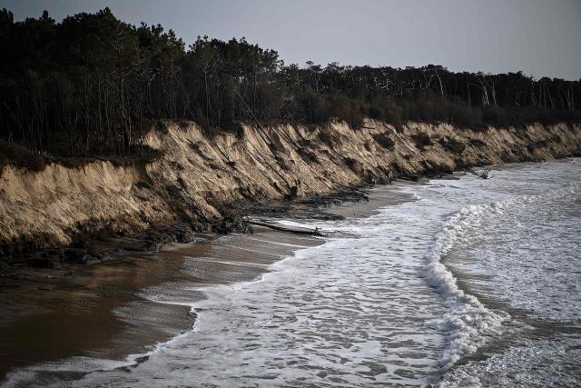 This aerial photograph shows waves breaking on the shoreline at the bottom of a cliff damaged by winter storms triggering the fall of pine trees along the Atlantic Ocean in Soulac-sur-Mer, south-western France on March 4, 2026. Severe winter storms seriously damaged the coastline of the Nouvelle-Aquitaine region with coastal erosion triggering the retreat of the coastline by several meters at places and threatening a camp site in Soulac-sur-Mer. (Photo by Christophe ARCHAMBAULT / AFP)