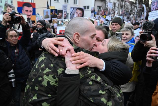 Olesya (C-R) kisses her husband Oleksandr (C-L), 43, a Ukrainian prisoner of war (POW), after he was released from 22 month of Russian captivity following a prisoner exchange in the Chernygiv region on March 5, 2026, amid the Russian invasion of Ukraine. Ukraine and Russia each freed 200 prisoners of war, the first part of an exchange that will see them swap 500 people each in total, officials said. (Photo by Genya SAVILOV / AFP)