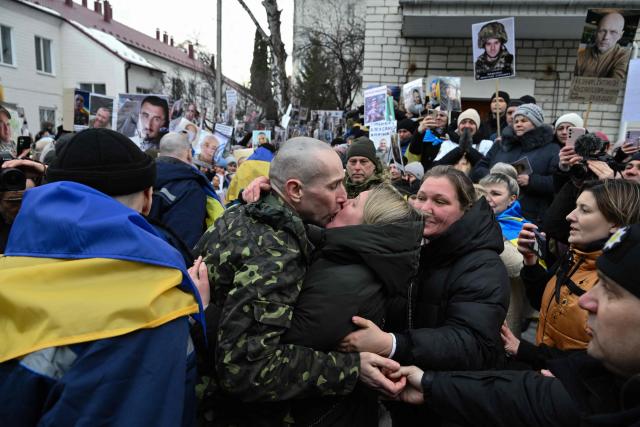 Olesya (C-R) kisses her husband Oleksandr (C-L), 43, a Ukrainian prisoner of war (POW), after he was released from 22 month of Russian captivity following a prisoner exchange in the Chernygiv region on March 5, 2026, amid the Russian invasion of Ukraine. Ukraine and Russia each freed 200 prisoners of war, the first part of an exchange that will see them swap 500 people each in total, officials said. (Photo by Genya SAVILOV / AFP)