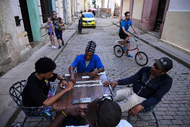 People play dominoes in a street during a blackout in Havana on March 5, 2026. Cuban authorities said on March 5, 2026 that electricity is slowly coming back to end a blackout that hit two-thirds of the beleaguered communist nation and stemmed from a lack of fuel under US pressure. (Photo by YAMIL LAGE / AFP)
