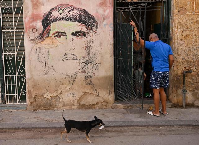 A man enters his home next to a mural depicting Argentine-born revolutionary leader, Ernesto "Che" Guevara, after a power outage in Havana on March 5, 2026. Cuban authorities said on March 5, 2026 that electricity is slowly coming back to end a blackout that hit two-thirds of the beleaguered communist nation and stemmed from a lack of fuel under US pressure. (Photo by YAMIL LAGE / AFP)