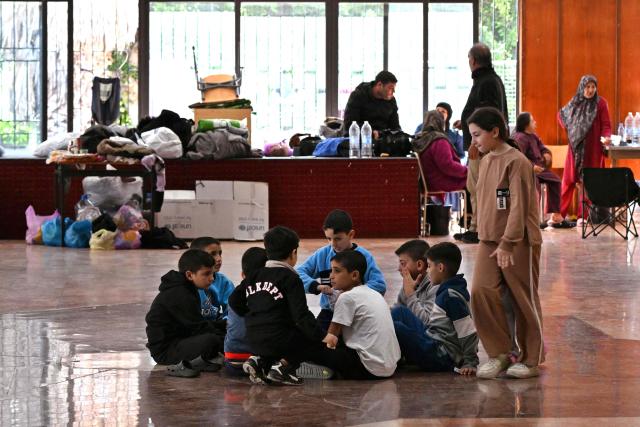 Children chat as they sit at a school transformed into a shelter for displaced people in the town of Dekwaneh north of Beirut on March 5, 2026. Israel bombarded Lebanon on March 2, expanding the conflict across the region after the massive Israel-US attack on Iran that the US president launched to topple Tehran's ruling clerics, and killing their supreme leader on February 28. (Photo by Joseph EID / AFP)