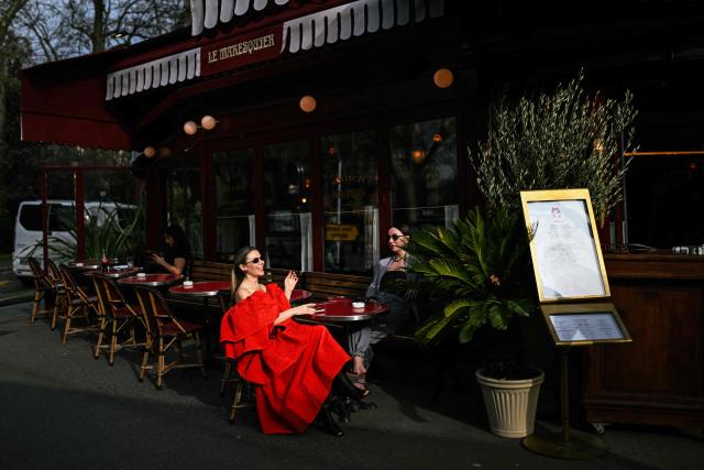 A woman wearing a red dress laughs at the terrace of a restaurant following a show of the Women's Ready to Wear Fall/Winter 2026-2027 of the Paris Women Fashion Week, in Paris, on March 5, 2026. (Photo by Julie SEBADELHA / AFP)