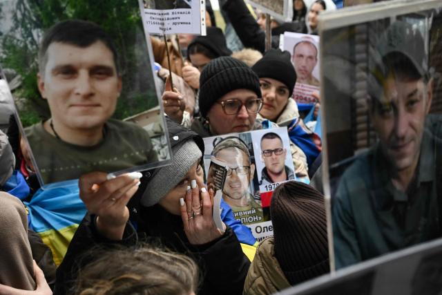Families hold portraits of their missing or captured relatives and friends as released Ukrainian prisoners of war (POW) arrive after a prisoners exchange in the Chernigiv region on March 5, 2026, amid the Russian invasion of Ukraine. Ukraine and Russia each freed 200 prisoners of war, the first part of an exchange that will see them swap 500 people each in total, officials said. (Photo by Genya SAVILOV / AFP)