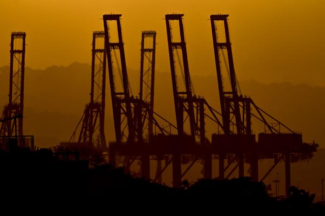 (FILES) The silhouettes of the container cranes in the Port of Balboa, managed by CK Hutchison Holdings based in Hong Kong, are seen during sunset at the entrance to the Panama Canal in Panama City on February 24, 2026. The two ports of the Panama Canal under the control of the Panamanian government following the cancellation of the contract with Hong Kong-based CK Hutchison Holdings are operating normally, the minister responsible told AFP on March 5, 2026. (Photo by MARTIN BERNETTI / AFP)