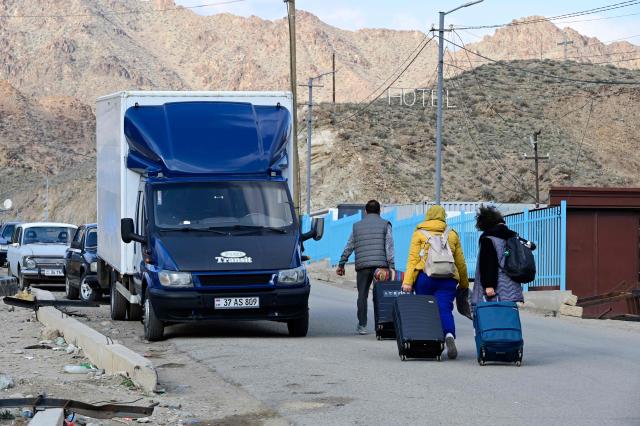 Iranian refugees carry luggage after crossing the border from Iran to Armenia at a border check point in the southern Armenian town of Gyumri, on March 5, 2026, amid the Middle East war. The United States and Israel began a sweeping military campaign against Iran, targeting missile facilities, naval assets and other infrastructure, with strikes triggering retaliatory attacks across the region. (Photo by KAREN MINASYAN / AFP)