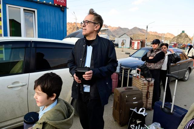 Iranian refugees stand next to luggage after crossing the border from Iran to Armenia at a border check point in the southern Armenian town of Gyumri, on March 5, 2026, amid the Middle East war. The United States and Israel began a sweeping military campaign against Iran, targeting missile facilities, naval assets and other infrastructure, with strikes triggering retaliatory attacks across the region. (Photo by KAREN MINASYAN / AFP)