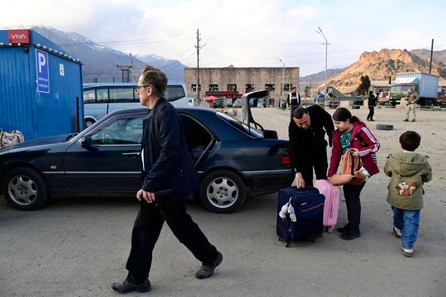 Iranian refugees stand next to luggage after crossing the border from Iran to Armenia at a border check point in the southern Armenian town of Gyumri, on March 5, 2026, amid the Middle East war. The United States and Israel began a sweeping military campaign against Iran, targeting missile facilities, naval assets and other infrastructure, with strikes triggering retaliatory attacks across the region. (Photo by KAREN MINASYAN / AFP)