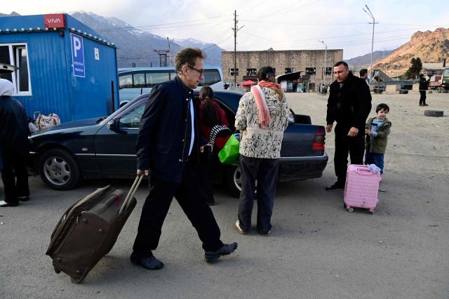 Iranian refugees carry luggage after crossing the border from Iran to Armenia at a border check point in the southern Armenian town of Gyumri, on March 5, 2026, amid the Middle East war. The United States and Israel began a sweeping military campaign against Iran, targeting missile facilities, naval assets and other infrastructure, with strikes triggering retaliatory attacks across the region. (Photo by KAREN MINASYAN / AFP)