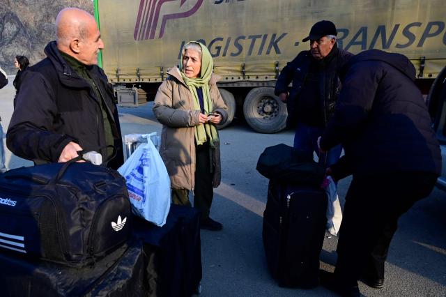 Iranian refugees stand next to luggage after crossing the border from Iran to Armenia at a border check point in the southern Armenian town of Gyumri, on March 5, 2026, amid the Middle East war. The United States and Israel began a sweeping military campaign against Iran, targeting missile facilities, naval assets and other infrastructure, with strikes triggering retaliatory attacks across the region. (Photo by KAREN MINASYAN / AFP)