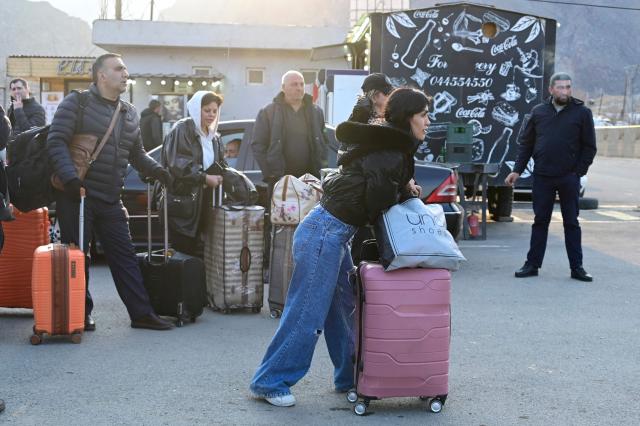 Iranian refugees stand next to luggage after crossing the border from Iran to Armenia at a border check point in the southern Armenian town of Gyumri, on March 5, 2026, amid the Middle East war. The United States and Israel began a sweeping military campaign against Iran, targeting missile facilities, naval assets and other infrastructure, with strikes triggering retaliatory attacks across the region. (Photo by KAREN MINASYAN / AFP)