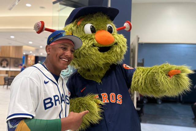 Infielder Osvaldo Carvalho poses for a photo with Orbit, the mascot of the Houston Astros, during the 2026 World Baseball Classic, at the Daikin Stadium in Houston, Texas, on March 5, 2026. Considered as an underdog in this competition but with a Silver Medal at the 2023 Pan American Games, the Team Brazil roster is a mix of Brazilian-born players, Japanese-Brazilian talent, children of MLB players, and athletes developed in the US minor leagues. (Photo by Moisés ÁVILA / AFP)