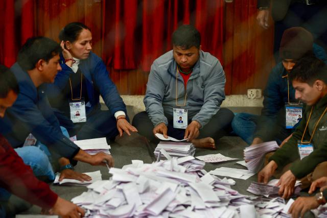 Electoral officials sit on the floor as they count votes at the counting centre after voting ended in Nepal's general election in Kathmandu on March 5, 2026. Nepal voted on March 5 for a new parliament in a high-stakes showdown between an entrenched old guard and a powerful youth movement, six months after deadly anti-corruption protests toppled the government. (Photo by PRABIN RANABHAT / AFP)