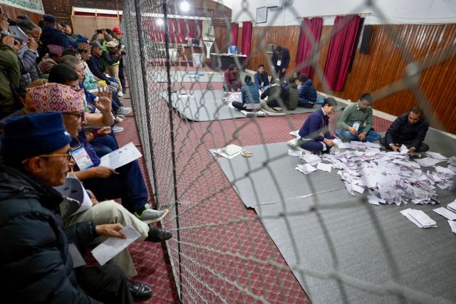 Electoral officials sit on the floor as they count votes at the counting centre after voting ended in Nepal's general election in Kathmandu on March 5, 2026. Nepal voted on March 5 for a new parliament in a high-stakes showdown between an entrenched old guard and a powerful youth movement, six months after deadly anti-corruption protests toppled the government. (Photo by Prabin Ranabhat / AFP)