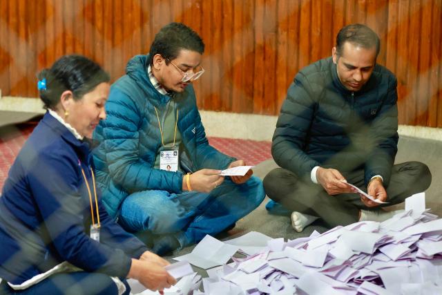 Electoral officials sit on the floor as they count votes at the counting centre after voting ended in Nepal's general election in Kathmandu on March 5, 2026. Nepal voted on March 5 for a new parliament in a high-stakes showdown between an entrenched old guard and a powerful youth movement, six months after deadly anti-corruption protests toppled the government. (Photo by PRABIN RANABHAT / AFP)