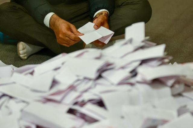 An electoral official sits on the floor as he counts votes at the counting centre after voting ended in Nepal's general election in Kathmandu on March 5, 2026. Nepal voted on March 5 for a new parliament in a high-stakes showdown between an entrenched old guard and a powerful youth movement, six months after deadly anti-corruption protests toppled the government. (Photo by PRABIN RANABHAT / AFP)