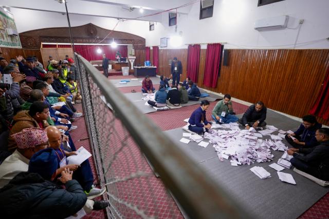 Electoral officials sit on the floor as they count votes at the counting centre after voting ended in Nepal's general election in Kathmandu on March 5, 2026. Nepal voted on March 5 for a new parliament in a high-stakes showdown between an entrenched old guard and a powerful youth movement, six months after deadly anti-corruption protests toppled the government. (Photo by Prabin Ranabhat / AFP)