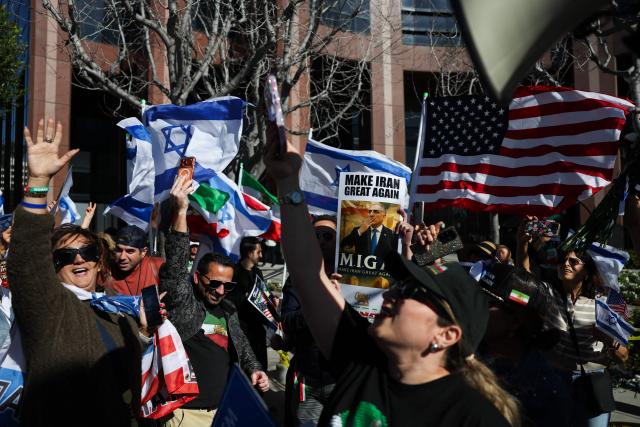 People hold signs in support of Reza Pahlavi, son of the last shah of Iran, as they wave flags and chant during a gathering of Iranian community members showing support for Israel and the United States, outside the Consulate General of Israel in Los Angeles, on March 5, 2026. (Photo by Patrick T. Fallon / AFP)
