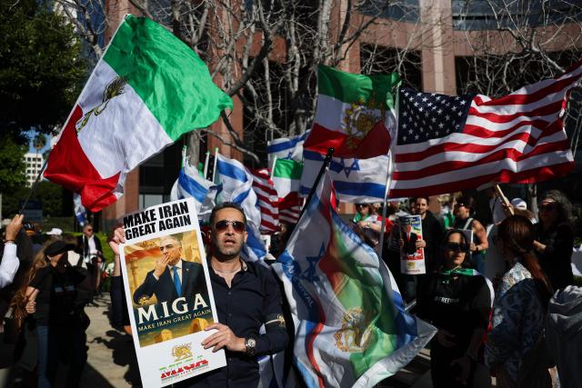 People hold signs in support of Reza Pahlavi, son of the last shah of Iran, as they wave flags and chant during a gathering of Iranian community members showing support for Israel and the United States, outside the Consulate General of Israel in Los Angeles, on March 5, 2026. (Photo by Patrick T. Fallon / AFP)