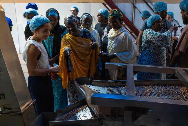 Members of the Mothers of Chibok interact with factory staff during their visit to the Nutzy Peanut Butter factory in Lagos on February 27, 2026. Nine women from Chibok are collaborating with Zenfix Nigeria, a company that sells peanuts and nut products, and Arjena Foods, producer of the Nutzy peanut butter brand, which is very popular in Nigeria. 
This partnership was supported by Joel Kachi Benson, director of the documentary "Mothers of Chibok," released in theaters last week, which chronicles the lives of these mothers. 
Before the creation of Mothers of Chibok, their harvests were sold unprocessed to middlemen in the village, generating meager and unpredictable incomes. Today, they work has better value, they obtain a stable income, and reach a wider audience. 
These women's peanut production increased from 15 100kg bags to 27 bags between 2024 and 2025.
For Ajrena Foods and Zenfix Nigeria, the initiative is part of a social and economic reconstruction project that could inspire other mothers whose children have also been abducted by Boko Haram, other jihadist groups, or criminal gangs. (Photo by TOYIN ADEDOKUN / AFP)