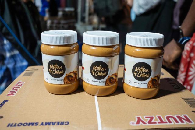 Processed Nutzy Mothers of Chibok product line stand during a visit to the peanut butter factory in Lagos on February 27, 2026. Nine women from Chibok are collaborating with Zenfix Nigeria, a company that sells peanuts and nut products, and Arjena Foods, producer of the Nutzy peanut butter brand, which is very popular in Nigeria. 
This partnership was supported by Joel Kachi Benson, director of the documentary "Mothers of Chibok," released in theaters last week, which chronicles the lives of these mothers. 
Before the creation of Mothers of Chibok, their harvests were sold unprocessed to middlemen in the village, generating meager and unpredictable incomes. Today, they work has better value, they obtain a stable income, and reach a wider audience. 
These women's peanut production increased from 15 100kg bags to 27 bags between 2024 and 2025.
For Ajrena Foods and Zenfix Nigeria, the initiative is part of a social and economic reconstruction project that could inspire other mothers whose children have also been abducted by Boko Haram, other jihadist groups, or criminal gangs. (Photo by TOYIN ADEDOKUN / AFP)