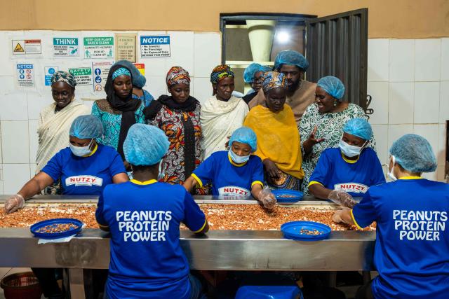 Mothers of Chibok observe factory workers processing peanuts during their visit to the Nutzy peanut butter factory in Lagos on February 27, 2026. Nine women from Chibok are collaborating with Zenfix Nigeria, a company that sells peanuts and nut products, and Arjena Foods, producer of the Nutzy peanut butter brand, which is very popular in Nigeria. 
This partnership was supported by Joel Kachi Benson, director of the documentary "Mothers of Chibok," released in theaters last week, which chronicles the lives of these mothers. 
Before the creation of Mothers of Chibok, their harvests were sold unprocessed to middlemen in the village, generating meager and unpredictable incomes. Today, they work has better value, they obtain a stable income, and reach a wider audience. 
These women's peanut production increased from 15 100kg bags to 27 bags between 2024 and 2025.
For Ajrena Foods and Zenfix Nigeria, the initiative is part of a social and economic reconstruction project that could inspire other mothers whose children have also been abducted by Boko Haram, other jihadist groups, or criminal gangs. (Photo by TOYIN ADEDOKUN / AFP)