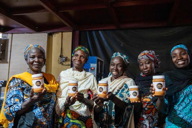 Mothers of Chibok pose for a photograph holing the Nutzy Mothers of Chibok product line during their visit to the Nutzy peanut butter factory in Lagos on February 27, 2026. Nine women from Chibok are collaborating with Zenfix Nigeria, a company that sells peanuts and nut products, and Arjena Foods, producer of the Nutzy peanut butter brand, which is very popular in Nigeria. 
This partnership was supported by Joel Kachi Benson, director of the documentary "Mothers of Chibok," released in theaters last week, which chronicles the lives of these mothers. 
Before the creation of Mothers of Chibok, their harvests were sold unprocessed to middlemen in the village, generating meager and unpredictable incomes. Today, they work has better value, they obtain a stable income, and reach a wider audience. 
These women's peanut production increased from 15 100kg bags to 27 bags between 2024 and 2025.
For Ajrena Foods and Zenfix Nigeria, the initiative is part of a social and economic reconstruction project that could inspire other mothers whose children have also been abducted by Boko Haram, other jihadist groups, or criminal gangs. (Photo by TOYIN ADEDOKUN / AFP)