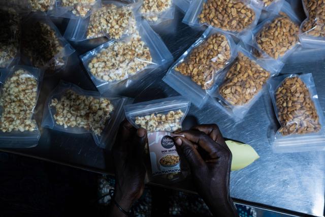 A woman affixes a Mothers of Chibok Pop Nut product-line label during their visit to the factory in Lagos on February 27, 2026. Nine women from Chibok are collaborating with Zenfix Nigeria, a company that sells peanuts and nut products, and Arjena Foods, producer of the Nutzy peanut butter brand, which is very popular in Nigeria. 
This partnership was supported by Joel Kachi Benson, director of the documentary "Mothers of Chibok," released in theaters last week, which chronicles the lives of these mothers. 
Before the creation of Mothers of Chibok, their harvests were sold unprocessed to middlemen in the village, generating meager and unpredictable incomes. Today, they work has better value, they obtain a stable income, and reach a wider audience. 
These women's peanut production increased from 15 100kg bags to 27 bags between 2024 and 2025.
For Ajrena Foods and Zenfix Nigeria, the initiative is part of a social and economic reconstruction project that could inspire other mothers whose children have also been abducted by Boko Haram, other jihadist groups, or criminal gangs. (Photo by TOYIN ADEDOKUN / AFP)
