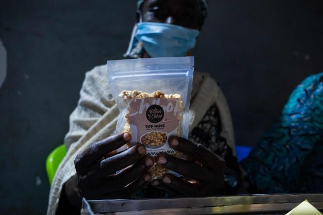 A woman holds a “Mothers of Chibok” Pop Nut product line item during their visit to the factory in Lagos on February 27, 2026. Nine women from Chibok are collaborating with Zenfix Nigeria, a company that sells peanuts and nut products, and Arjena Foods, producer of the Nutzy peanut butter brand, which is very popular in Nigeria. 
This partnership was supported by Joel Kachi Benson, director of the documentary "Mothers of Chibok," released in theaters last week, which chronicles the lives of these mothers. 
Before the creation of Mothers of Chibok, their harvests were sold unprocessed to middlemen in the village, generating meager and unpredictable incomes. Today, they work has better value, they obtain a stable income, and reach a wider audience. 
These women's peanut production increased from 15 100kg bags to 27 bags between 2024 and 2025.
For Ajrena Foods and Zenfix Nigeria, the initiative is part of a social and economic reconstruction project that could inspire other mothers whose children have also been abducted by Boko Haram, other jihadist groups, or criminal gangs. (Photo by TOYIN ADEDOKUN / AFP)