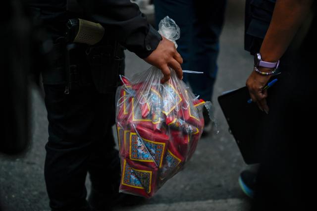 A police officer carries the fireworks evidence after masked protesters who were arrested with pyrotechnic bombs outside the National Congress, where a session for the election of two magistrates for the Constitutional Court was held in Guatemala City on March 5, 2026. (Photo by JOHAN ORDONEZ / AFP)