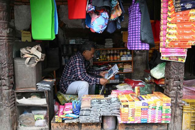 A shopkeeper reads a newspaper at his shop in Kathmandu on March 6, 2026 a day after Nepal's Parliamentary election. Counting was underway in Nepal on March 6, after a high-stakes parliamentary election that could reshape the country's leadership following 2025 protests that toppled the government. (Photo by TAUSEEF MUSTAFA / AFP)