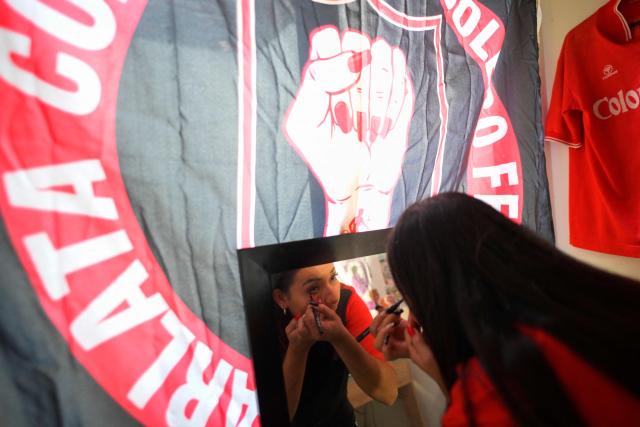 America de Cali's fan, Jessica Avila from the Colectivo Futbolero Escarlata, gets ready to attend the Copa Sudamericana football match between Colombia's America de Cali and Atletico Bucaramanga at the Olimpico Pascual Guerrero Stadium in Cali, Colombia on March 5, 2026. With a drum, a female fan sets the pace for the chants of a feminist fan club at the stadium in the Colombian city of Manizales. "One, two, three!" she says like an orchestra conductor surrounded exclusively by women tired of machismo in football, as is the case in other countries such as Brazil. (Photo by JOAQUIN SARMIENTO / AFP)