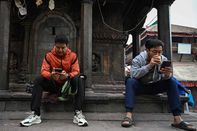 People watch election results on their mobile phones at the Durbar Square in Kathmandu on March 6, 2026 a day after Nepal's Parliamentary election. Counting was underway in Nepal on March 6, after a high-stakes parliamentary election that could reshape the country's leadership following 2025 protests that toppled the government. (Photo by Prakash MATHEMA / AFP)
