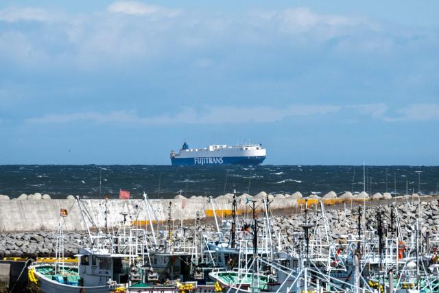 This picture taken on March 5, 2026 shows a car carrier ship sailing at the coast near the Tokyo Electric Power Company's (TEPCO) Fukushima Daiichi Nuclear Power Plant (not seen), as seen from Ukedo fishing port in Namie, Fukushima prefecture. (Photo by Philip FONG / AFP)