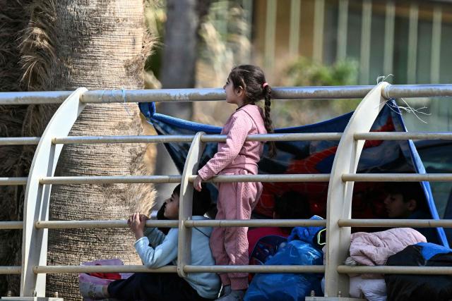 Children look on as displaced residents who fled Israeli airstrikes in Beirut's southern suburbs take shelter along the corniche waterfront in the Lebanese capital on March 6, 2026. Fresh strikes rocked Iran and Lebanon on March 6, as Israel vowed to escalate to a new phase in the Middle East war that has spiralled rapidly throughout the region and beyond. (Photo by Joseph EID / AFP)