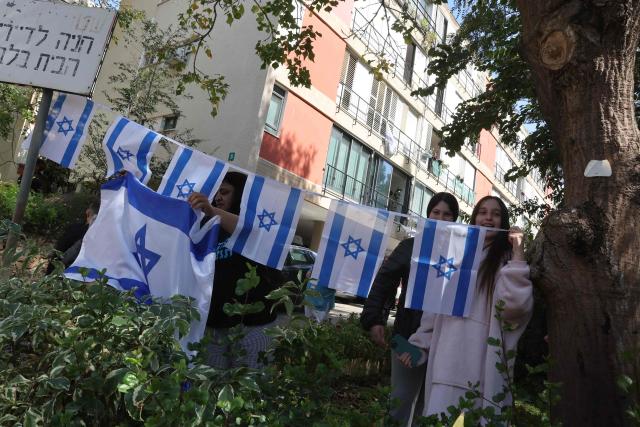 People brandish Israeli flags following an Iranian strike in Givatayim, in the center of Israel on March 6, 2026. The war broke out on February 28 after US and Israeli strikes on Iran which responded by attacking US bases in Gulf countries and mainland Israel with drone and missiles strikes. (Photo by Jack GUEZ / AFP)