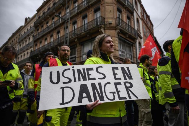 A protestor holds a placard reading "Factories in danger" during a demonstration by Fibre Excellence employees and unions as two factories in Saint-Gaudens and Tarascon are threatened with closure in Toulouse, southwestern France on March 6, 2026. (Photo by Ed JONES / AFP)