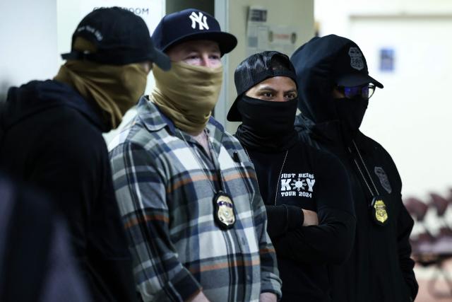 Masked federal agents stand in a hallway at the New York Federal Plaza Immigration Court inside the Jacob K. Javitz Federal Building in New York on March 6, 2026. US President Donald Trump has made deporting undocumented immigrants a key priority for his second term, after successfully campaigning against an alleged "invasion" by criminals. (Photo by CHARLY TRIBALLEAU / AFP)