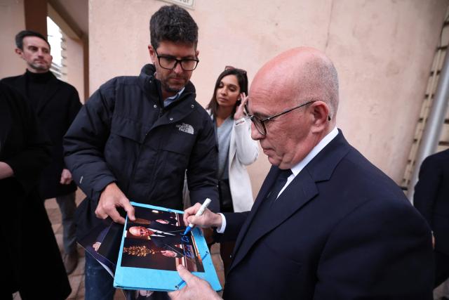 EDITORS NOTE: Graphic content / President of French right-wing Union des Droites pour la Republique (UDR) party and Nice mayoral candidate Eric Ciotti (R) signs autographs ahead of attending a campaign rally to support the French far-right party Rassemblement National (RN) party Menton mayoral candidate, ahead of France's municipal elections in Menton, southeastern France on March 6, 2026. French voters head to the polls for municipal elections on March 15 and 22, 2026. (Photo by Valery HACHE / AFP)