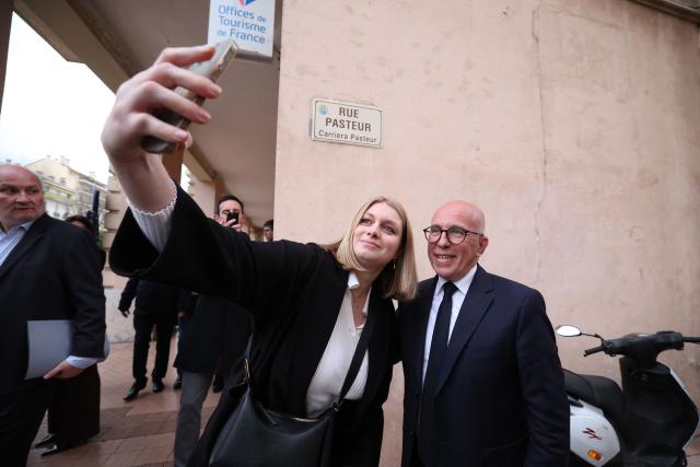 EDITORS NOTE: Graphic content / President of French right-wing Union des Droites pour la Republique (UDR) party and Nice mayoral candidate Eric Ciotti (R) poses for a selfie as he arrives to attending a campaign rally to support the French far-right party Rassemblement National (RN) party Menton mayoral candidate, ahead of France's municipal elections in Menton, southeastern France on March 6, 2026. French voters head to the polls for municipal elections on March 15 and 22, 2026. (Photo by Valery HACHE / AFP)