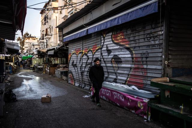 A man walks past closed shops in Carmel market in Tel Aviv, on March 6, 2026. Israel's military on March 6 said that Iran had launched cluster bombs "multiple times" since the start of the war that began with a US-Israeli attack on the Islamic republic last week. (Photo by OLYMPIA DE MAISMONT / AFP)